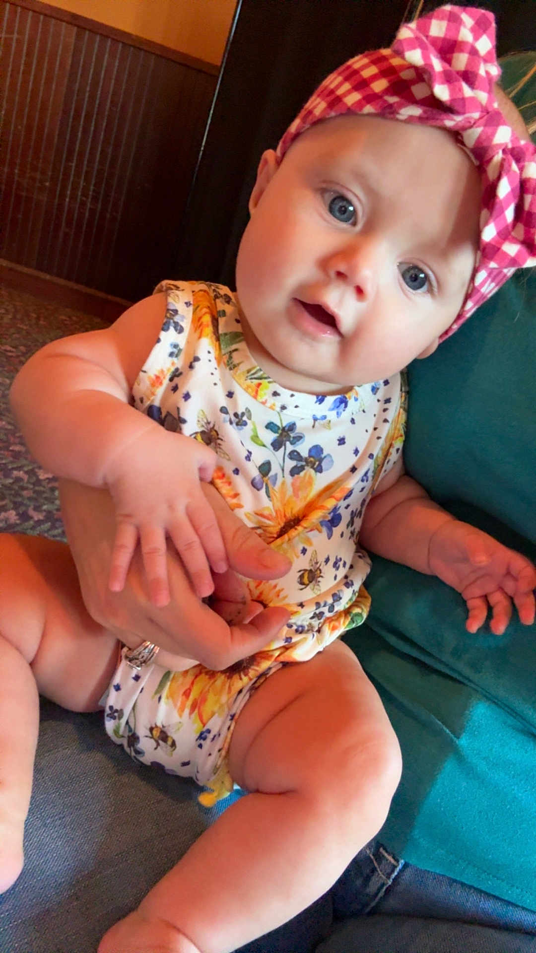Patsy joined the competition — help win amazing prizes! adult_hand, baby, blue_eyes, child, comfort, couch, curious_expression, floral_pattern, hand, headband, indoor, infant, lap, onesie, person, pink, sitting, skin, white, yellow