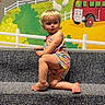 Patsy is registered to the contest to win money with this photo: background, blond_hair, bright_colors, bus, carpet, cartoon, child, colorful_clothing, expression, face, fence, indoor, kneeling, mural, person, playful, smile, stairs, toddler, train