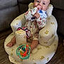Patsy is registered to the contest to win money with this photo: baby, infant, child, inflatable_chair, teddy_bear_pattern, floral_onesie, bib, blue_eyes, toy, foot, hand, sitting, chewing, indoor, floor, wooden_floor, comfortable, cute, playful, happy