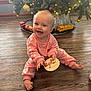 baby, child, smiling, pink_outfit, wooden_floor, christmas_tree, holiday, decorations, lights, ornaments, toy_train, happy, sitting, indoor, person, cute, infant, plush, festive, sign