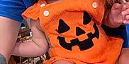 Patsy joined the competition — help win amazing prizes! arm, baby, blue_shirt, bow, child, cute, expression, face, festive, furniture, hair, headband, holiday, indoor, orange_clothing, person, pumpkin_outfit, skin, table, tattoo