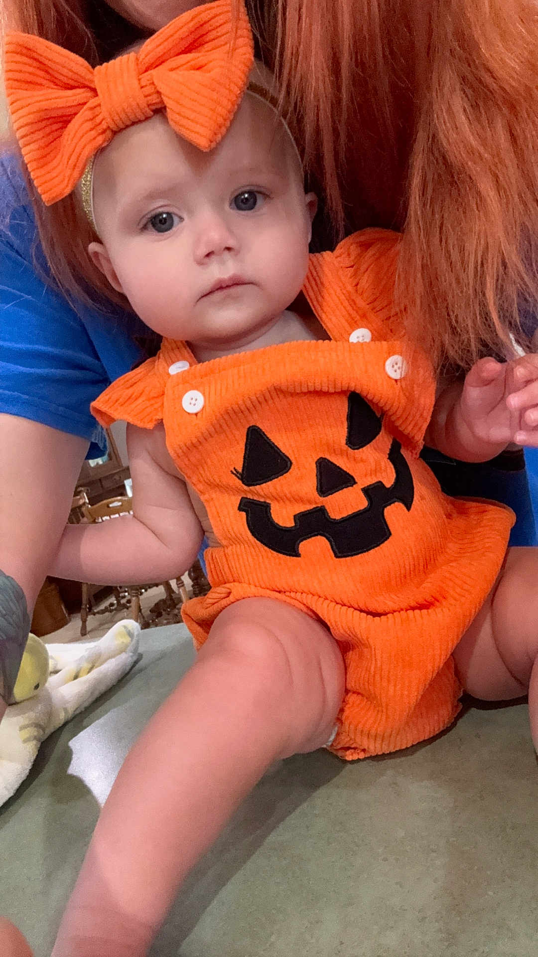 Patsy joined the competition — help win amazing prizes! baby, child, pumpkin_outfit, orange_clothing, headband, bow, face, person, indoor, tattoo, arm, skin, table, furniture, hair, blue_shirt, cute, holiday, festive, expression