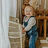 Patsy is registered to the contest to win money with this photo: baby, barefoot, candles, child, cozy, curtain, denim_overalls, floor, happy, home_decor, indoor, light, pampas_grass, person, rug, smile, standing, toddler, wicker_chair, wooden_table