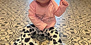 Patsy joined the competition — help win amazing prizes! baby, bow, child, clothing, cow_print, cute, eyes, floor, happy, headband, indoor, infant, long_sleeve, pants, patterned_floor, person, pink_shirt, sitting, smiling, toes