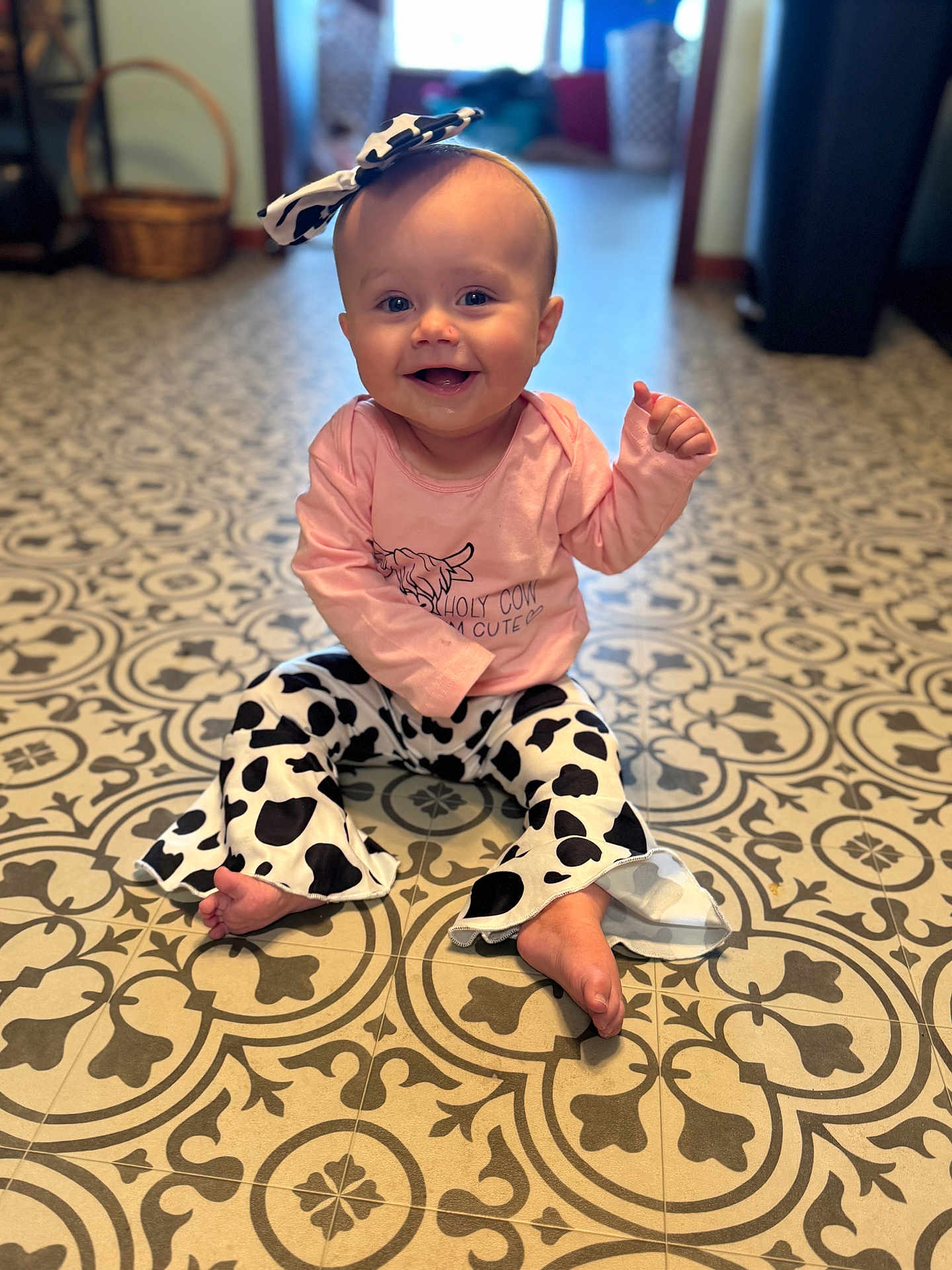 Patsy joined the competition — help win amazing prizes! baby, child, smiling, sitting, indoor, floor, patterned_floor, headband, bow, clothing, pants, long_sleeve, pink_shirt, cow_print, happy, cute, person, infant, toes, eyes