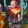 Patsy is registered to the contest to win money with this photo: baby, child, swing, playground_equipment, outdoor, sunlight, smiling, joyful, orange_clothing, plastic, footwearless, brick_wall, grill, seat, play_area, infant, happy, person, daylight, summer