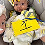 Patsy is registered to the contest to win money with this photo: baby, blanket, car_seat, child, clothing, cute, face, flower_bow, foot, headband, indoor, infant, number_one, person, portrait, safe, seatbelt, soft_toy, toy_elephant, yellow_card