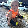 baby, child, infant, carpet, socks, batman, orange_clothing, indoor, furniture, chair, pillow, floor, curious, hair, cute, small_hands, patterned_rug, home, sitting, portrait