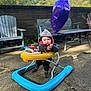 baby, balloon, hoodie, walker, outdoor, patio, child, toy, purple_balloon, concrete, bench, chair, sunlight, brick_wall, greenery, person, clothing, footwear, play, daytime