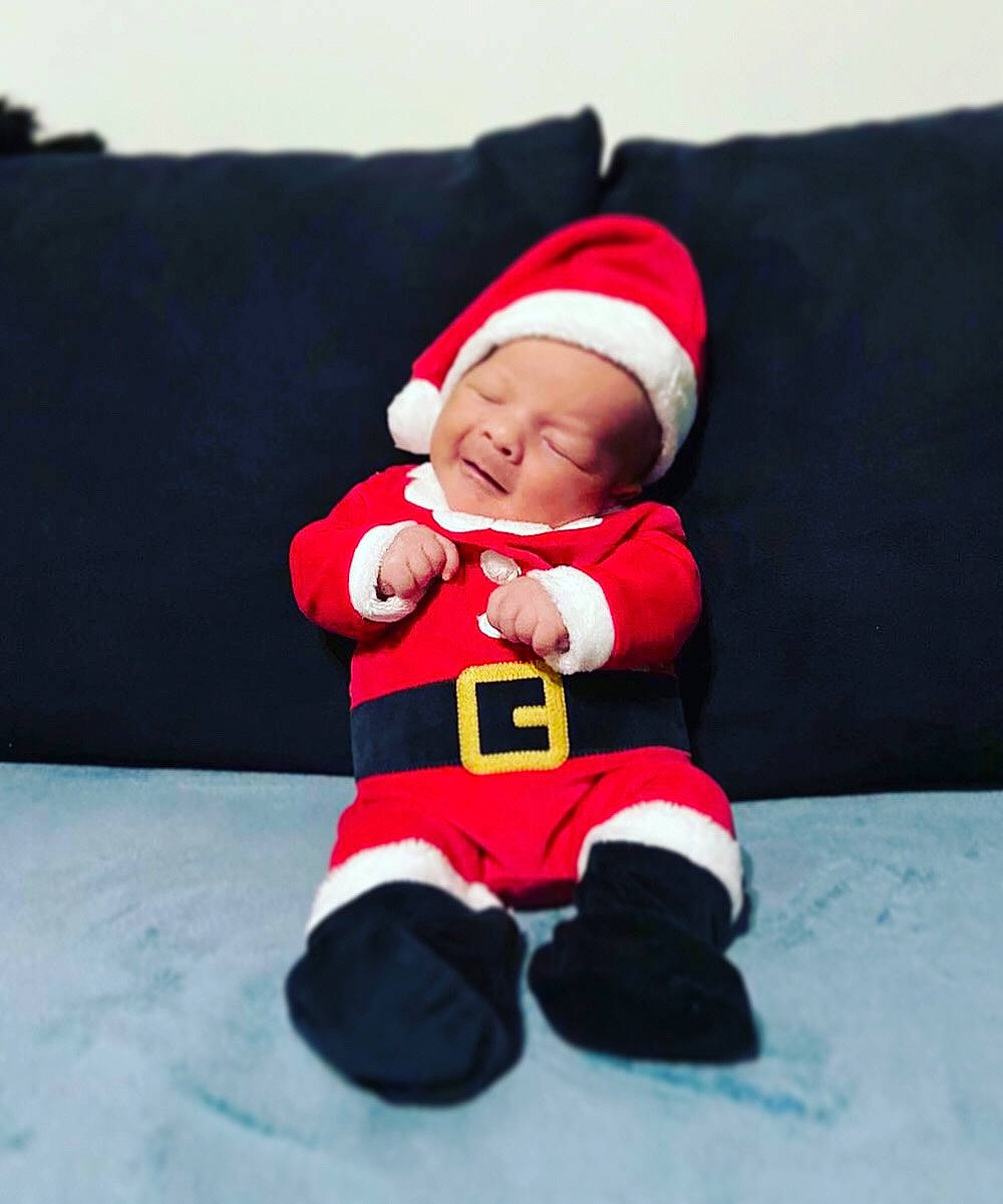 Nino participe au concours pour gagner de l'argent avec cette photo : baby, child, christmas, christmas_eve, fictional_character, headwear, holiday, lap, person, red, santa_claus, smile, toddler