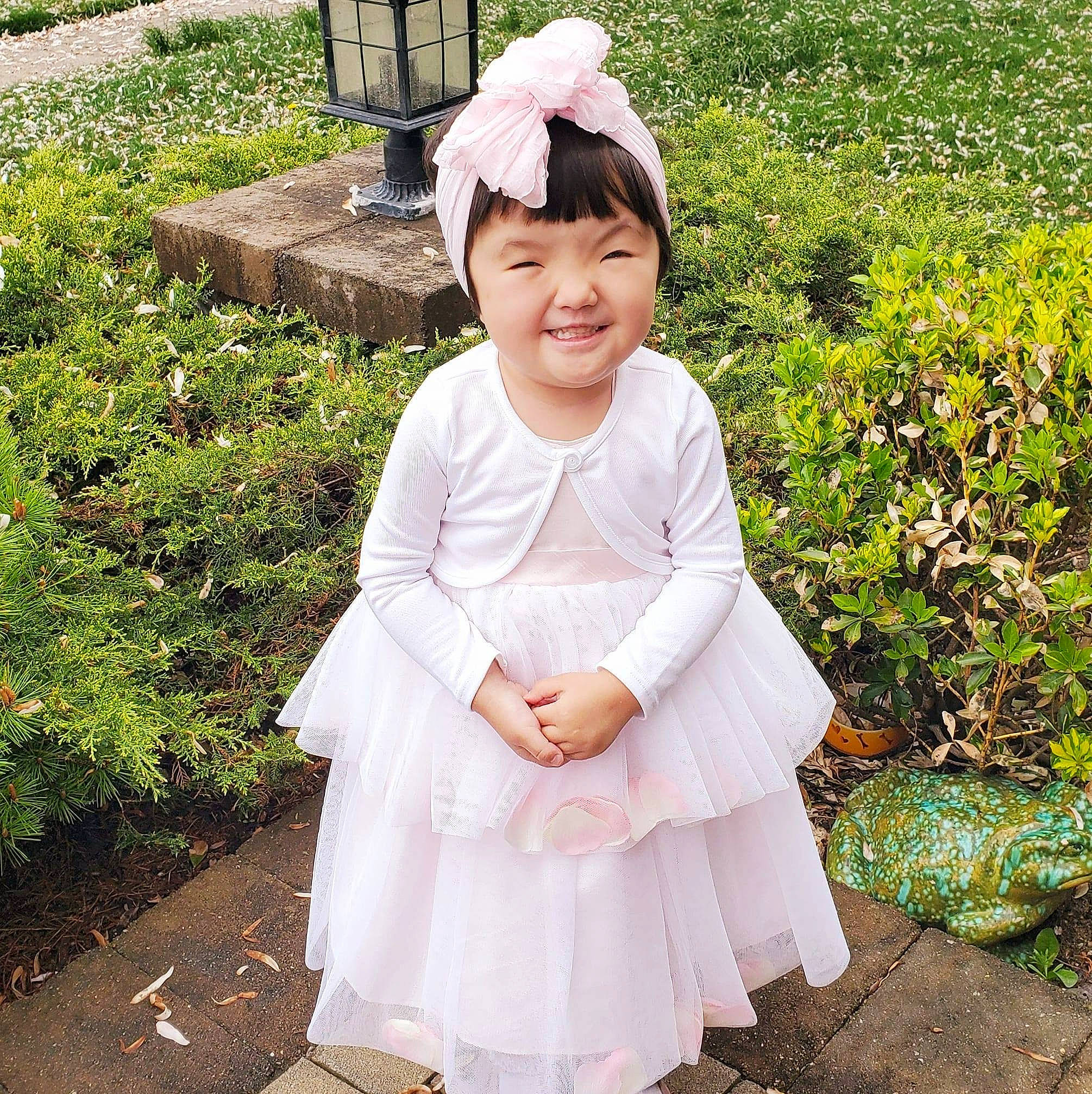 Lia is registered to the contest to win money with this photo: baby_toddler_clothing, botany, child, clothing, costume, dress, flower_girl, hair_accessory, happy, headgear, headwear, joy, person, petal, pink, plant, skin, sleeve, smile, textile