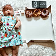 Karsyn joined the competition — help win amazing prizes! baby, blanket, blocks, bow, box, colorful, cute, donut, dress, face, food, headband, indoors, infant, lying_down, milestone, months, pattern, person, soft
