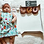 baby, blanket, blocks, bow, box, colorful, cute, donut, dress, face, food, headband, indoors, infant, lying_down, milestone, months, pattern, person, soft