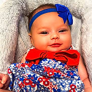 Maxie is registered to the contest to win money with this photo: baby, infant, child, smiling, headband, bow, blanket, floral_dress, red, blue, white, cute, cozy, plush, portrait, indoors, person, face, happy, sitting