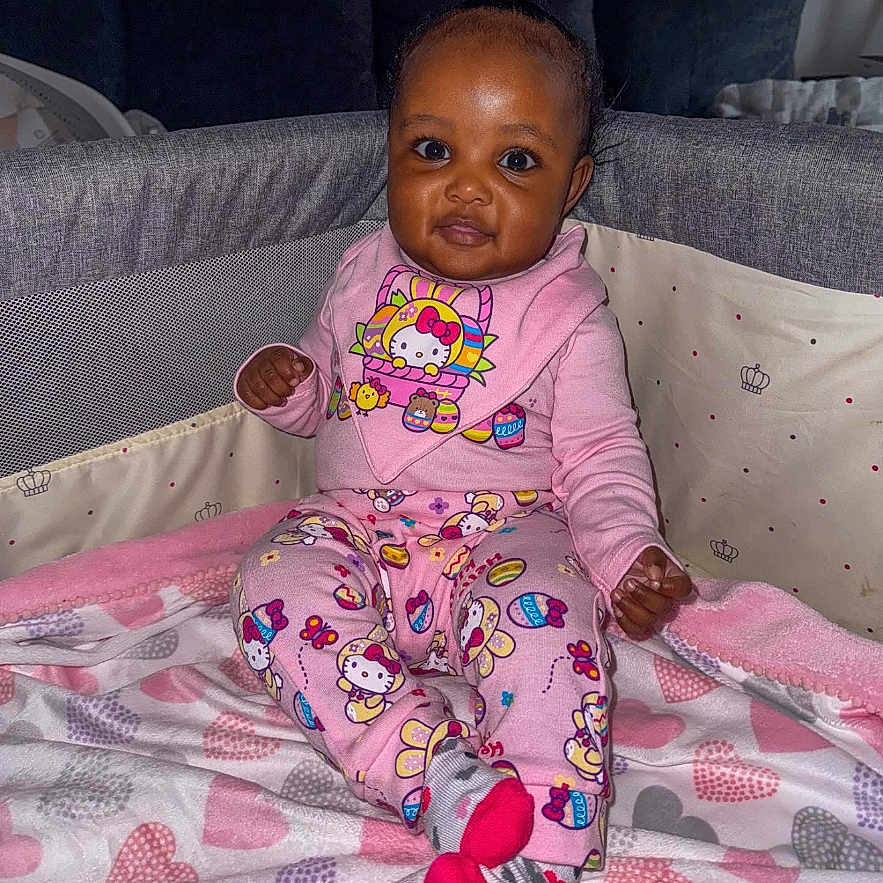 Journee joined the competition — help win amazing prizes! baby, blanket, child, cozy, cute, face, furniture, happy, heart, hello_kitty, indoor, pajamas, pattern, person, pink, playpen, portrait, seated, smile, socks