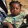 toddler, child, stroller, green_tshirt, star_wars, pacifier_clip, hand, face, outdoor, sunlight, serious_expression, black_hair, clothing, person, baby, seat, daylight, skin, holding, closeup