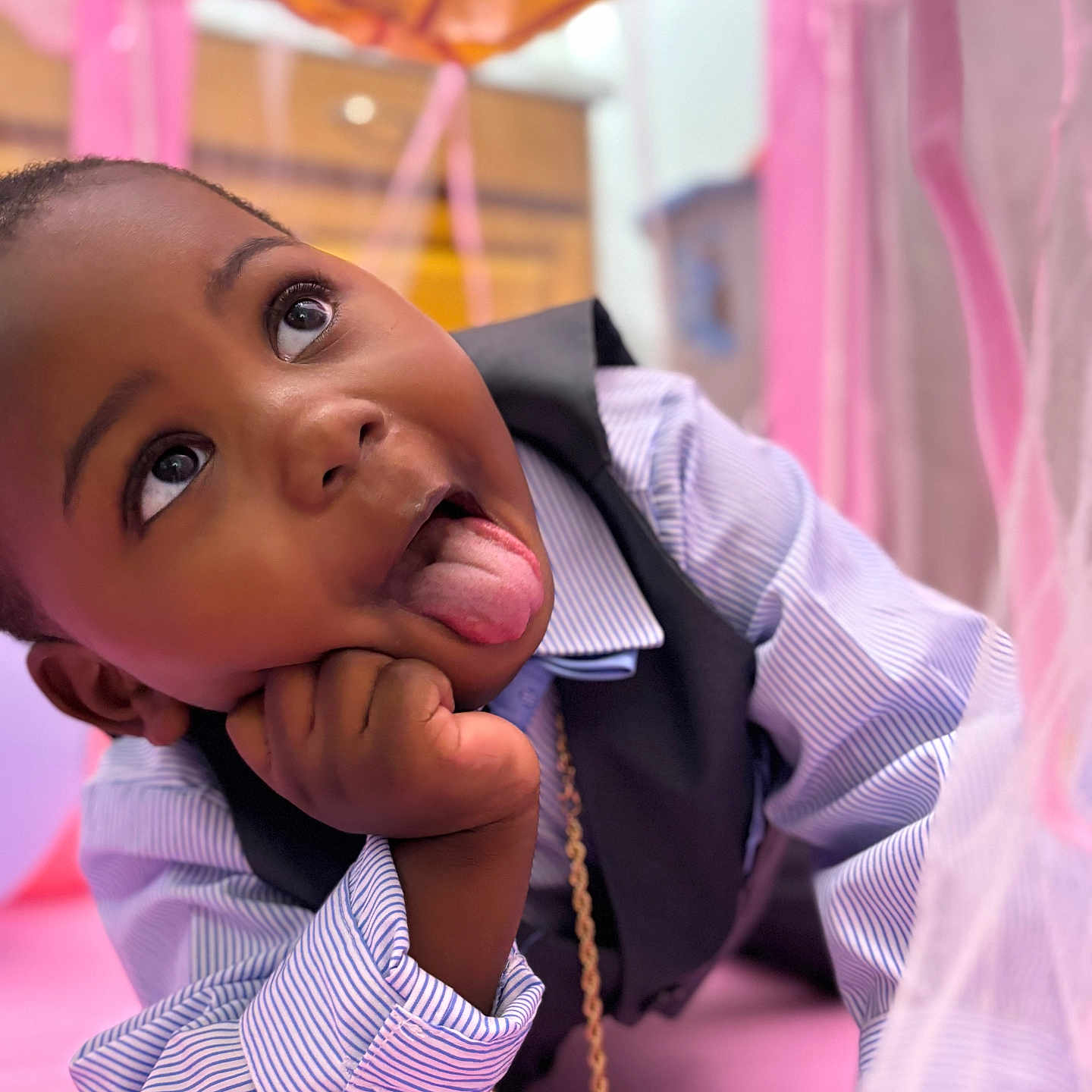 Khimerie is registered to the contest to win money with this photo: blurred_background, candid, casual, cheeky, child, cute, expression, face, hand, happy, indoors, lying_down, orange, pink, playful, portrait, striped_shirt, tongue, vest, young