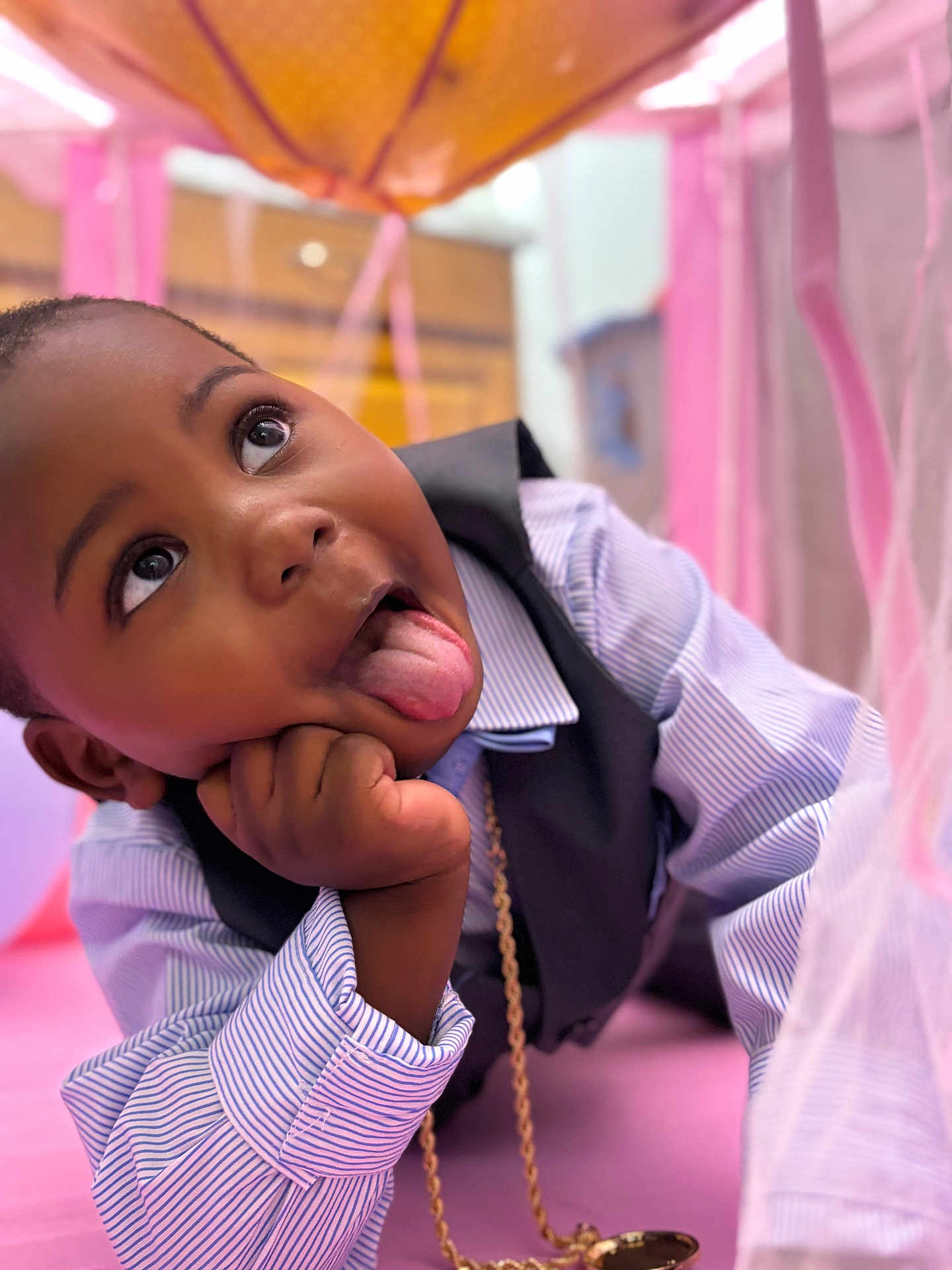 Khimerie is registered to the contest to win money with this photo: blurred_background, candid, casual, cheeky, child, cute, expression, face, hand, happy, indoors, lying_down, orange, pink, playful, portrait, striped_shirt, tongue, vest, young