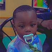 Khimerie is registered to the contest to win money with this photo: child, toddler, pacifier, bow_tie, plaid_shirt, table, indoor, person, face, chair, portrait, clothing, baby, seated, artwork, colorful, hand, background, expression, casual