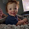 baby, child, toddler, smiling, happy, portrait, sitting, indoor, blanket, fluffy_blanket, gray, blue_shirt, red_hair, face, eyes, television, living_room, cozy, home, photograph