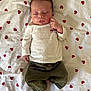 baby, sleeping, infant, heart_pattern, white_shirt, green_pants, bed_sheet, peaceful, cute, child, newborn, relaxed, lying_down, indoor, soft_lighting, portrait, small_hands, tiny_feet, cozy, adorable
