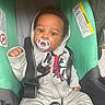 Kycen is registered to the contest to win money with this photo: baby, pacifier, car_seat, hoodie, infant, child, seatbelt, straps, clothing, curious, cute, indoor, warning_label, sitting, young_child, portrait, casual_wear, furniture, infancy, headwear
