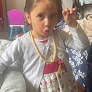 Zainab is registered to the contest to win money with this photo: bed, blanket, cardigan, chair, child, clothing, cute, dress, furniture, girl, hair, hairstyle, home, indoor, necklace, person, playful_expression, portrait, room, young