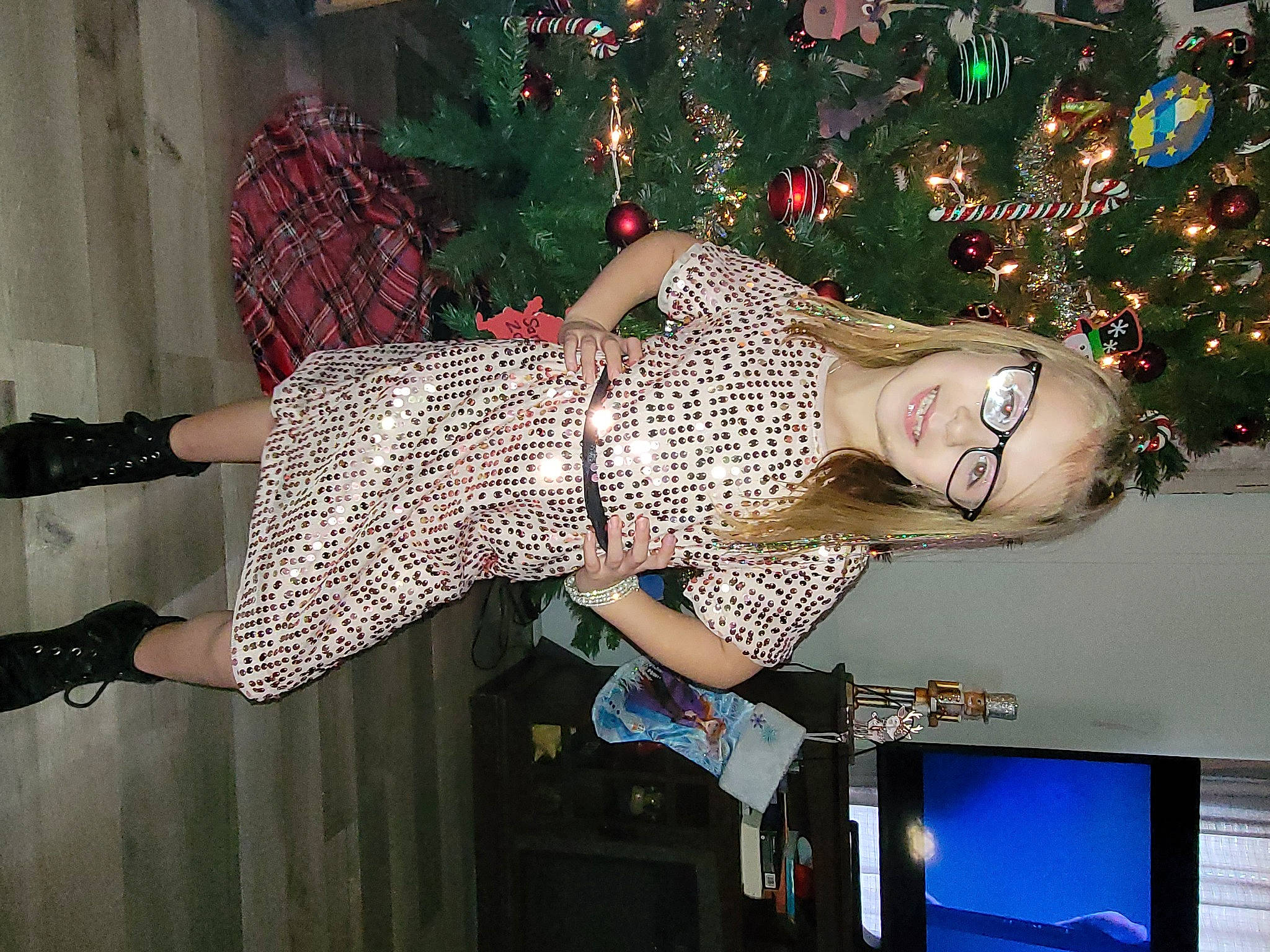 Sarah is registered to the contest to win money with this photo: christmas_decoration, christmas_ornament, christmas_tree, computer_monitor, event, fashion, fashion_design, fun, holiday, holiday_ornament, human_leg, joy, leg, ornament, pattern, person, red, standing, tartan, thigh