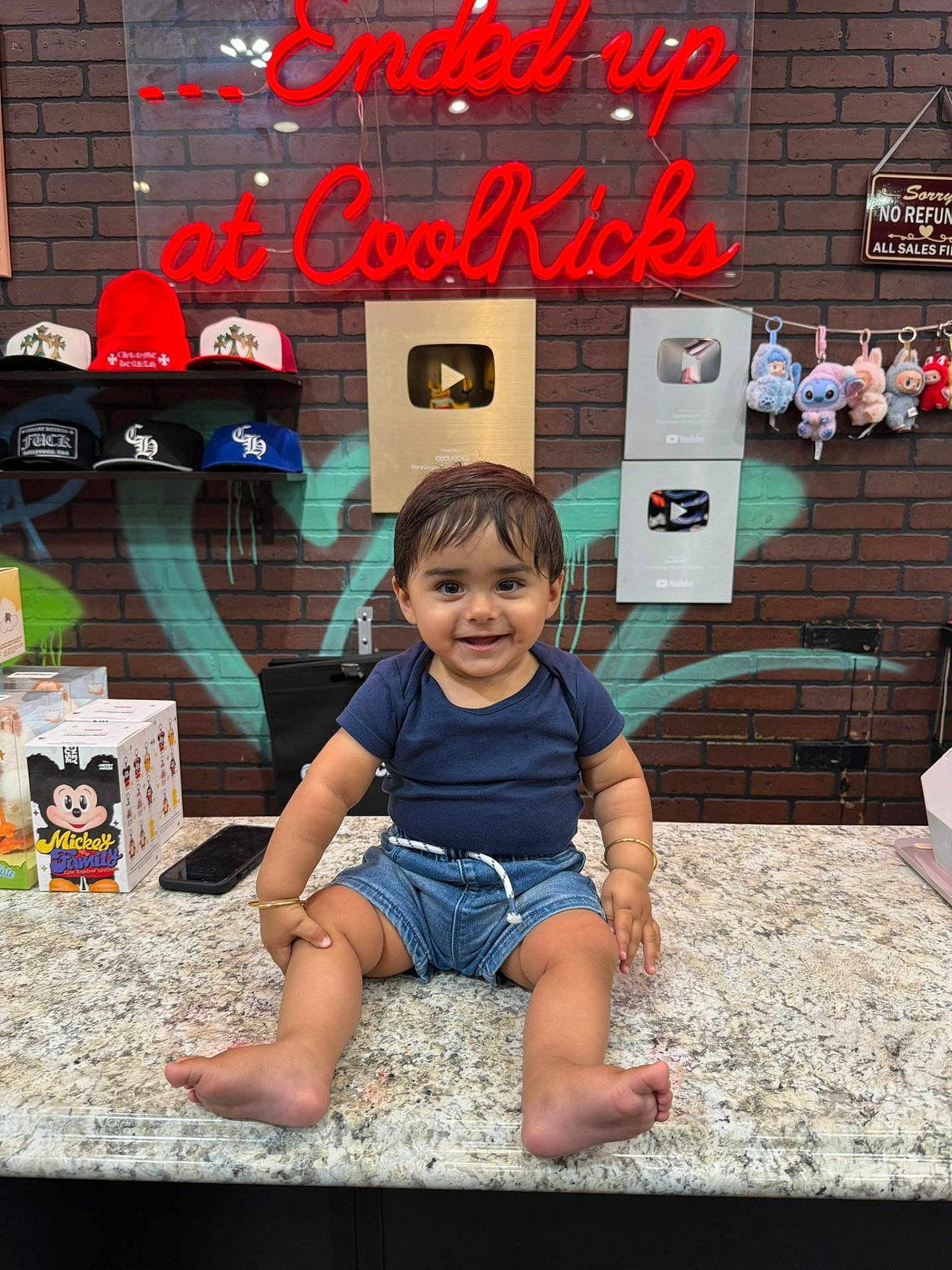 Sandro joined the competition — help win amazing prizes! toddler, child, smiling, countertop, brick_wall, neon_sign, graffiti, play_buttons, hats, plush_toys, store_interior, shorts, tshirt, bracelets, footwear_store, colorful, indoor, person, happy, cute
