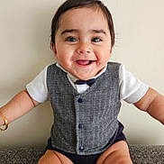 Sandro joined the competition — help win amazing prizes! baby, smiling, happy, vest, bow_tie, sitting, couch, child, infant, cute, portrait, indoor, clothing, face, arms, furniture, skin, person, expression, joy