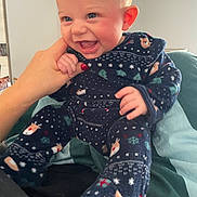 Gabriel participe au concours pour gagner de l'argent avec cette photo : baby, child, smiling, happy, pajamas, hand, finger, indoor, person, blue_eyes, face, cute, infant, clothing, sitting, joy, holiday, patterned_clothes, cozy, interaction