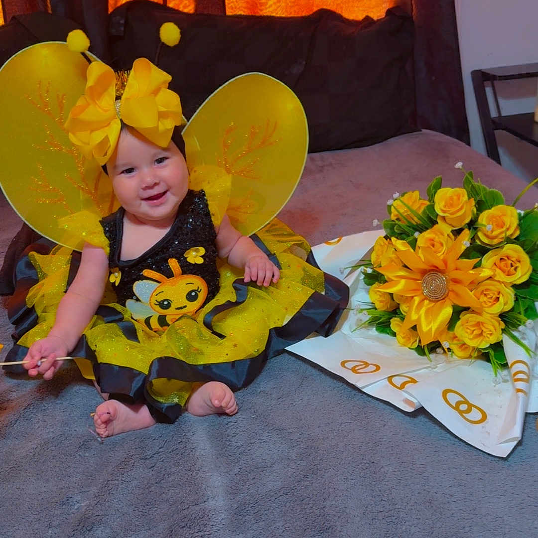 Montczerrath is registered to the contest to win money with this photo: baby, bee_costume, black, blanket, bouquet, child, costume, curtains, cute, decor, flowers, happy, headwear, indoors, portrait, sitting, smiling, toddler, wings, yellow