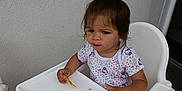Shirley a rejoint le concours — aidez-le/la à gagner de superbes lots ! cartoon_print, child, cute, expression, floor, floral_pattern, food, hair_clip, high_chair, indoor, person, seat, shirt, small, snack, table, toddler, wall, white, young