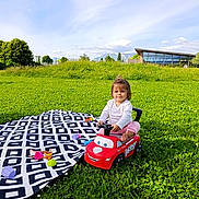 Shirley participe au concours pour gagner de l'argent avec cette photo : blanket, casual_clothing, child, clouds, daytime, fun, grass, greenery, happy, nature, outdoor, park, play, sky, smiling, sunlight, toddler, toy, toy_car, young_child