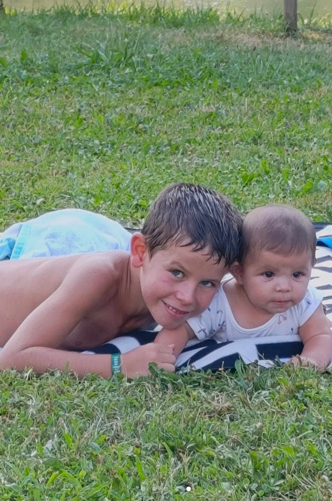 Ryan participe au concours pour gagner de l'argent avec cette photo : child, baby, grass, outdoor, blanket, smiling, happy, boy, infant, greenery, summer, nature, casual, playful, portrait, bare_chest, short_hair, toddler, sibling, relaxing