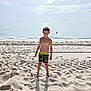 barefoot, beach, boy, child, clouds, daytime, ocean, outdoor, portrait, sand, shadow, shore, sky, smiling, summer, sunlight, swim_shorts, vacation, water, waves