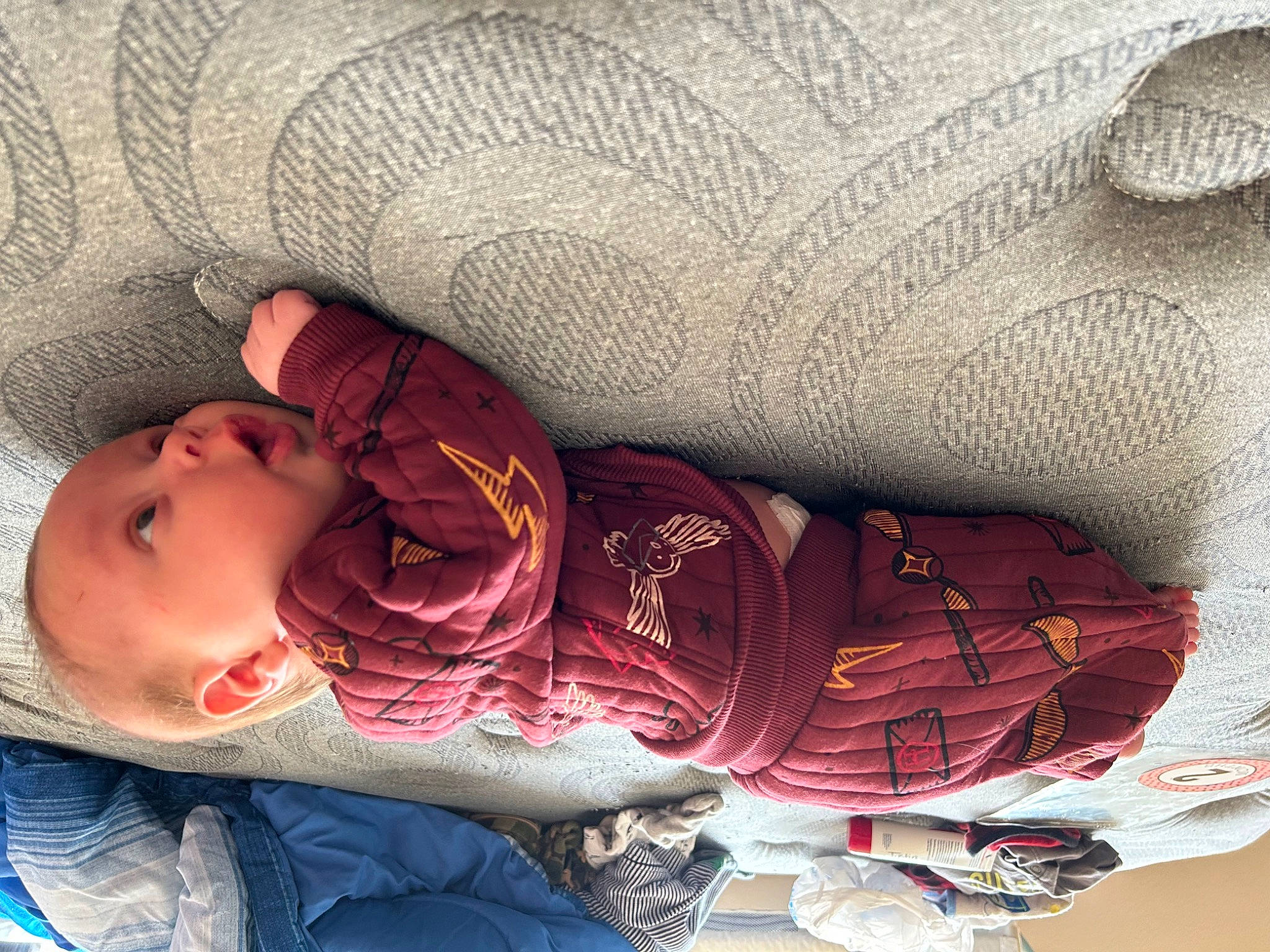 Axel is registered to the contest to win money with this photo: baby, baby_products, baby_toddler_clothing, carmine, child, comfort, elbow, flesh, headgear, human_leg, linens, mouth, pattern, person, sitting, skin, sleeve, textile, toddler, wood