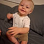 toddler, child, baby, person, indoor, bed, gray, shirt, shorts, smile, face, hand, foot, couch, clothing, happy, young, cute, light_skin, blond_hair