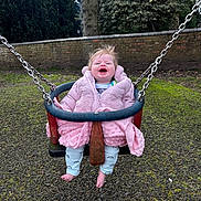 Amari is registered to the contest to win money with this photo: baby, clothing, coat, face, grass, head, jacket, nature, outdoorplayarea, outdoors, pants, park, person, photography, plant, playarea, portrait, swing, toy, tree