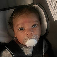 Kamari is registered to the contest to win money with this photo: baby, pacifier, car_seat, child, infant, face, straps, clothing, closeup, eyes, head, seatbelt, safety, person, young_child, indoors, cute, portrait, newborn, restraint