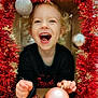 toddler, child, smiling, happy, curly_hair, christmas, ornament, holiday, festive, red_tinsel, decoration, gold_snowflakes, indoors, joyful, portrait, cute, holding, celebration, fun, face