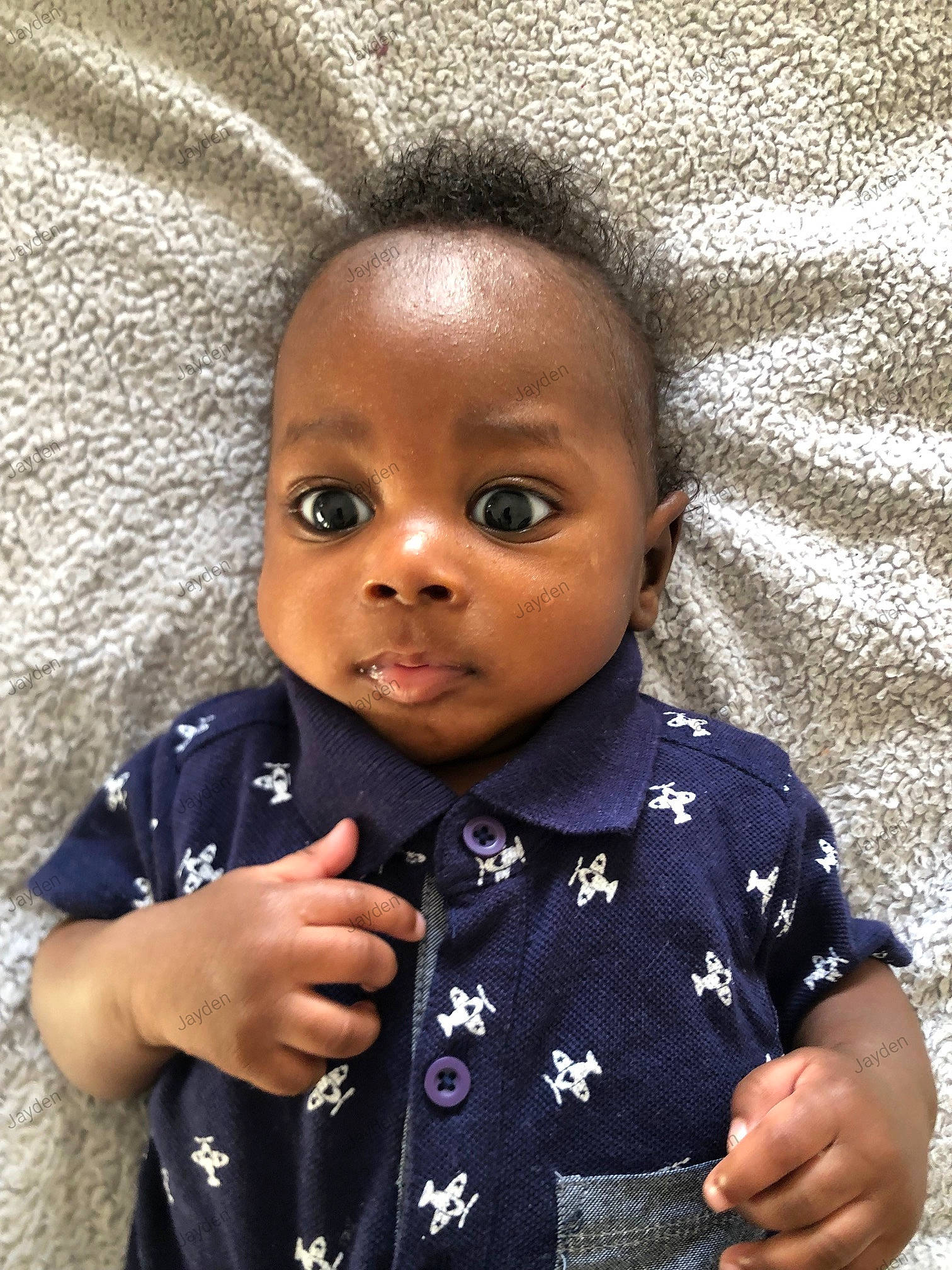 Jayden is registered to the contest to win money with this photo: arm, baby_toddler_clothing, cheek, chin, clothing, collar, eyebrow, facial_expression, finger, forehead, gesture, hand, happy, iris, lip, nose, organ, person, skin, sleeve