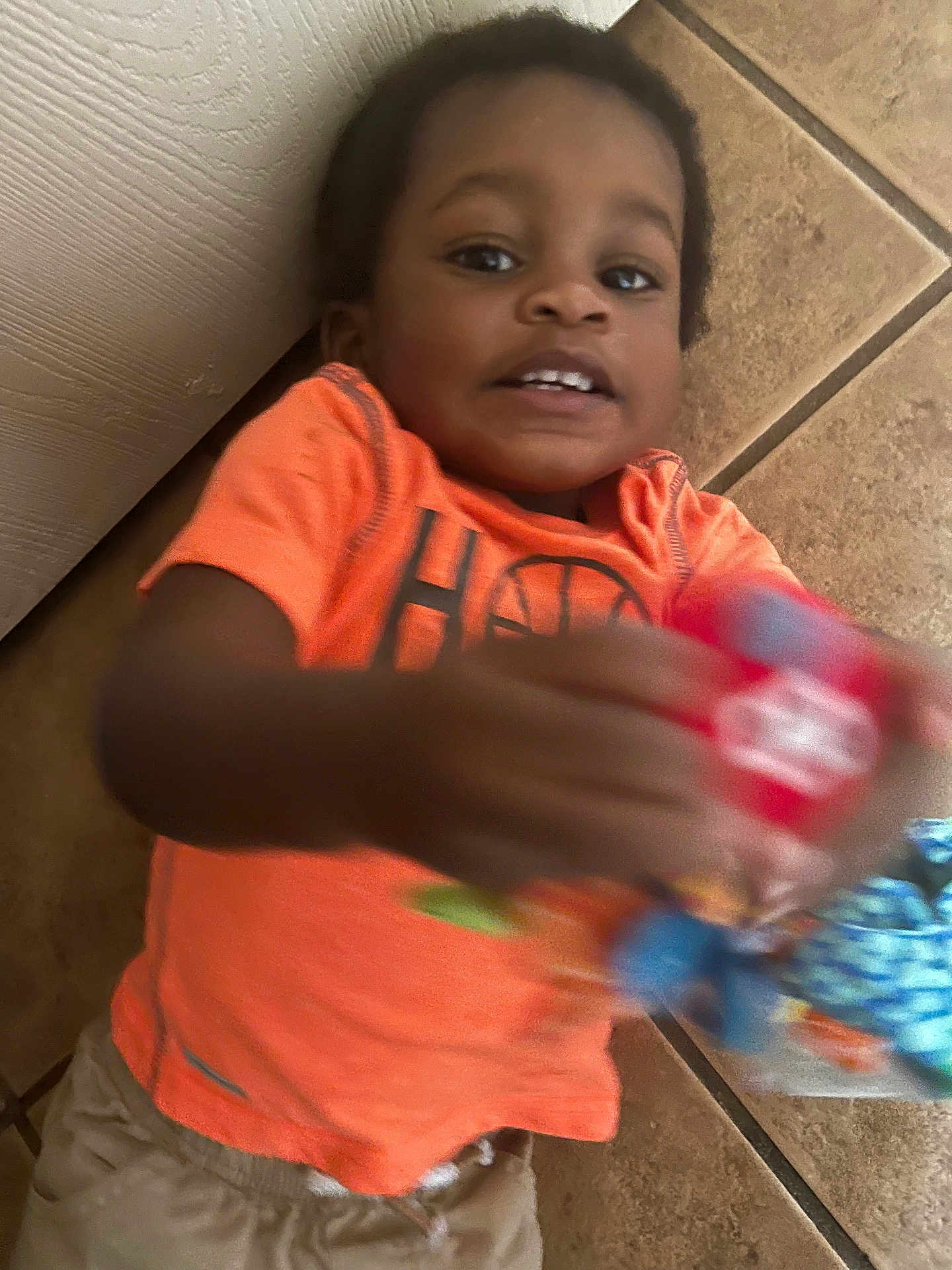 Zian joined the competition — help win amazing prizes! child, toddler, orange_shirt, toy, floor, tile, playful, motion_blur, indoor, person, casual_clothing, young_child, smiling, happy, hands, reaching, candid, portrait, head, skin