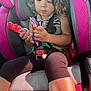 black_clothing, car_interior, car_seat, child, closeup, daylight, gray, hair, hands, legs, mermaid, person, pink, playing, purple_hair, red_hair, seatbelt, sitting, toddler, toy