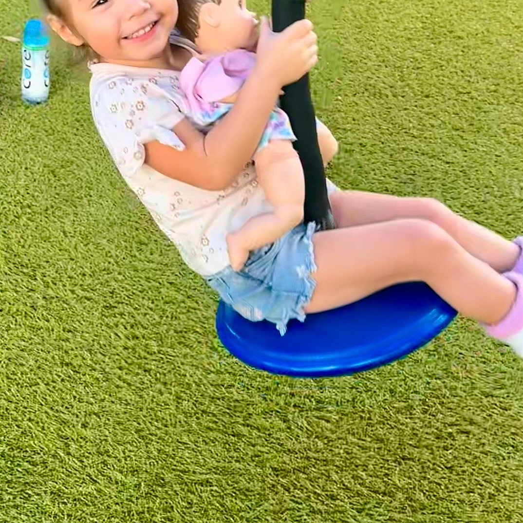 Delilah is registered to the contest to win money with this photo: casual_clothing, child, daylight, doll, feet, fun, girl, grass, happy, leisure, outdoor, person, play, playground, shorts, smile, summer, swing, toy, tshirt