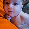 Penelopy is registered to the contest to win money with this photo: newborn, baby, infant, child, face, portrait, eyes, wide_eyed, looking_at_camera, lying_down, cuddling, orange_clothing, blanket, indoor, close_up, skin, hand, head, cozy, photography