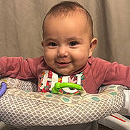 Alana is registered to the contest to win money with this photo: baby, infant, smiling, baby_walker, toy, pink_clothing, indoor, curtain, happy, child, face, person, seated, playful, young, cute, portrait, cozy, home, floor