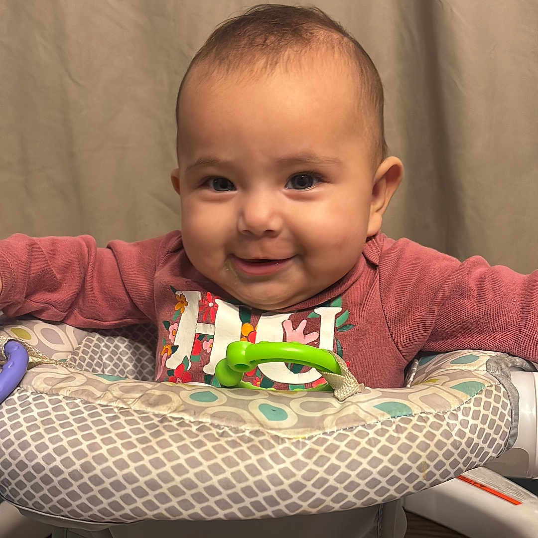 Alana is registered to the contest to win money with this photo: baby, infant, smiling, baby_walker, toy, pink_clothing, indoor, curtain, happy, child, face, person, seated, playful, young, cute, portrait, cozy, home, floor
