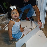 Jaylani joined the competition — help win amazing prizes! child, girl, bow, white_clothing, blue_skirt, tattoo, man, assembly, furniture, floor, indoor, curly_hair, casual_clothing, wooden_floor, instruction_sheet, home, family, kneeling, toy, interaction