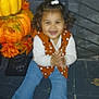 Jaylani joined the competition — help win amazing prizes! toddler, child, sitting, clapping, smiling, curly_hair, hair_tie, orange_vest, polka_dot, blue_pants, red_socks, pumpkins, autumn_leaves, fall_decor, festive, indoors, step, dark_background, happy, portrait